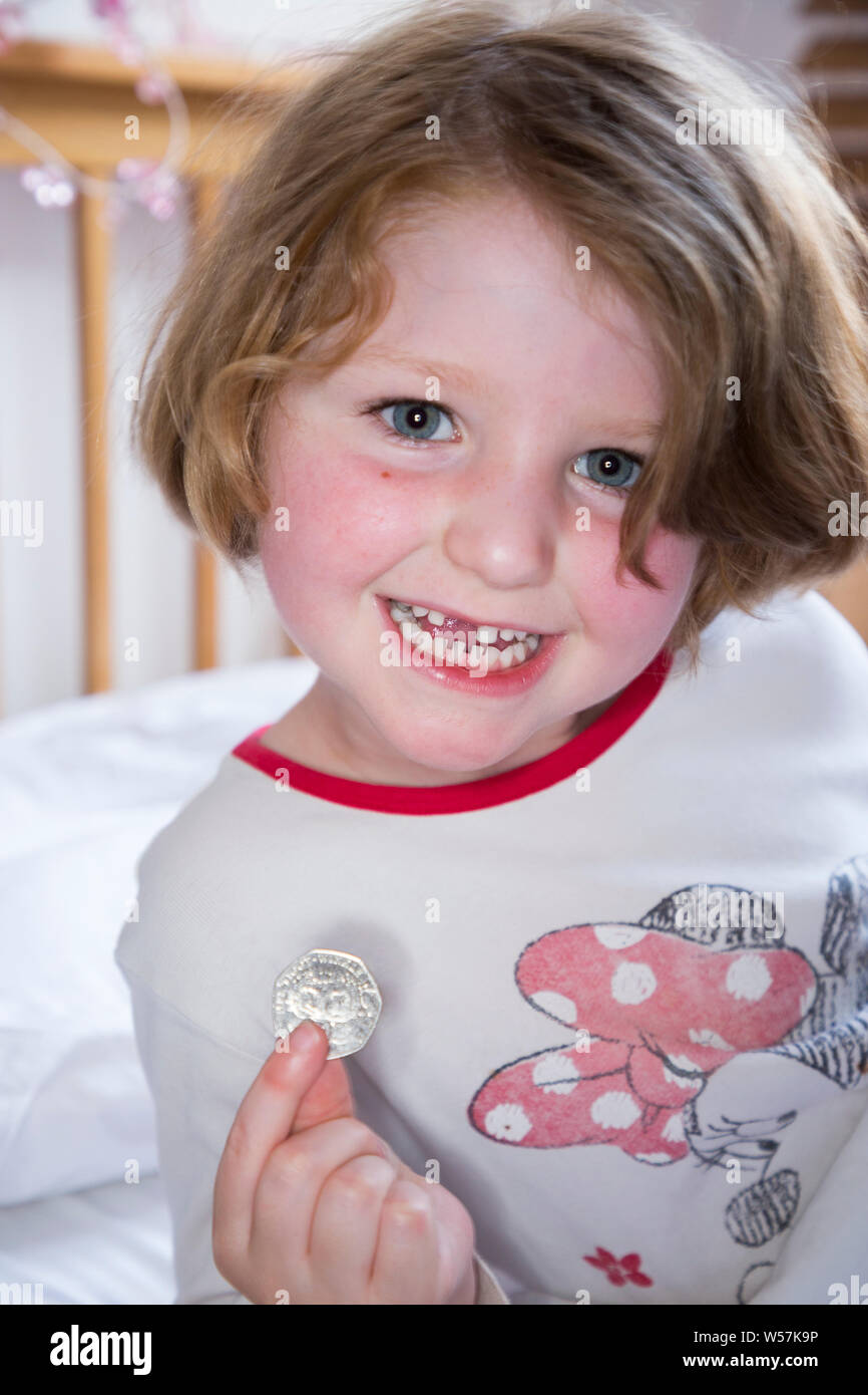 Young Girl smiling pour révéler une dent avant manquant / dents Dent, tout en maintenant un 50p / cinquante pence pièce dans laquelle sont arrivés de la fée de dent sous son oreiller. Royaume-uni (111) Banque D'Images