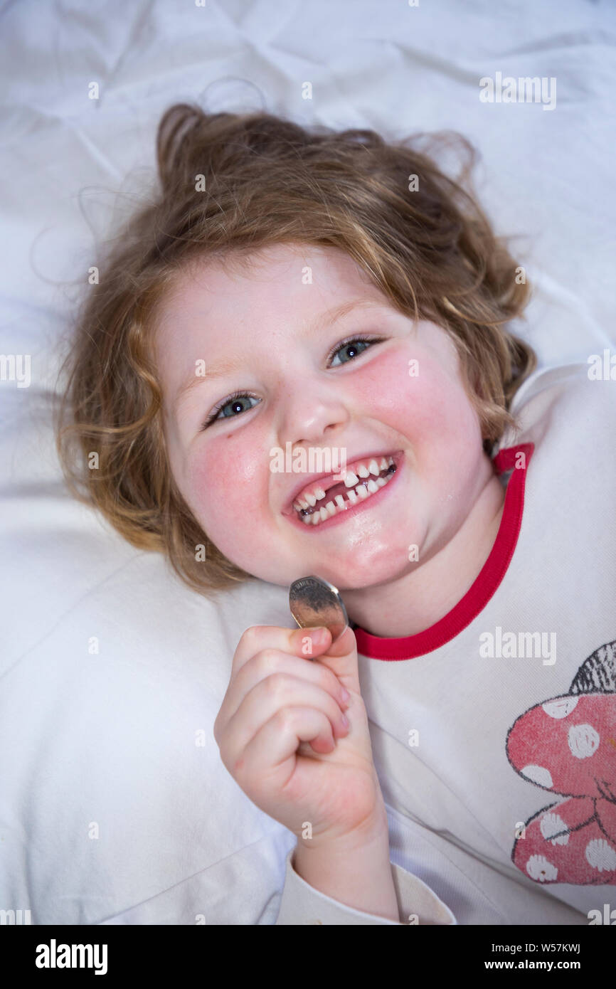 Young Girl smiling pour révéler une dent avant manquant / dents Dent, tout en maintenant un 50p / cinquante pence pièce dans laquelle sont arrivés de la fée de dent sous son oreiller. Royaume-uni (111) Banque D'Images