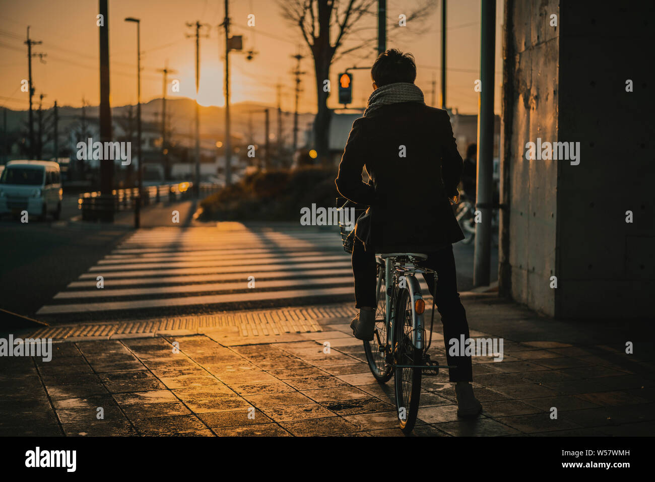Man riding bike en attente à traverser la route au coucher du soleil à Kyoto, Japon Banque D'Images