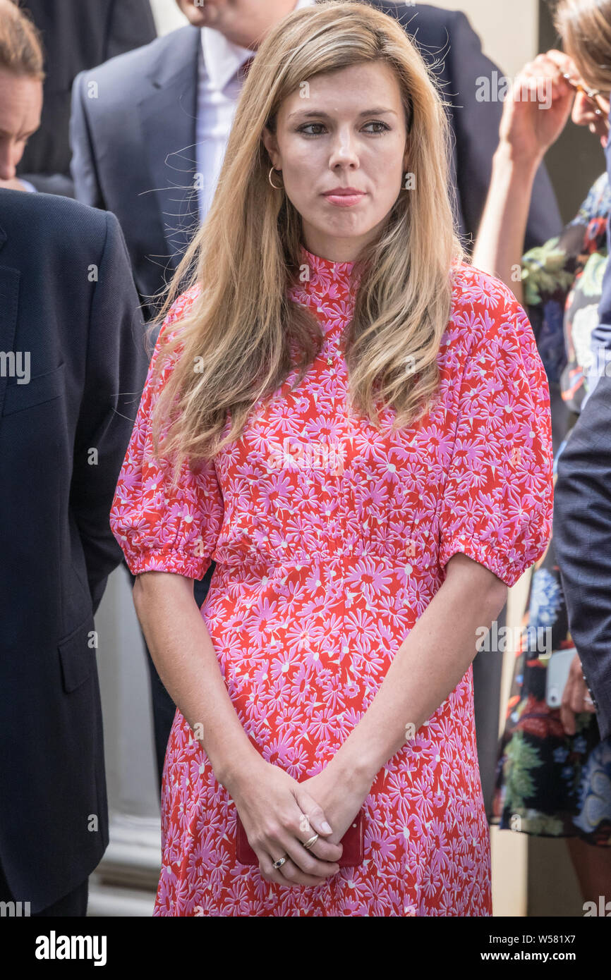 Boris Johnson's amie Carrie Symonds, en robe rose, attend à l'extérieur de 10 Downing Street pour l'arrivée du nouveau Premier Ministre Banque D'Images