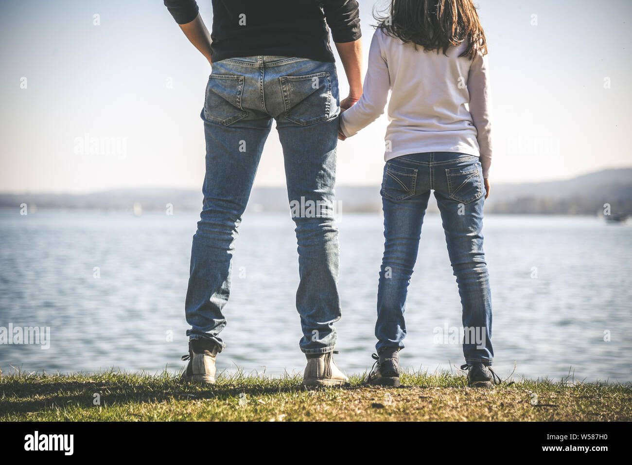 Père et fille se tenant la main près de la mer. Deux personnes debout sur le bord de la mer dans une belle journée ensoleillée. Papa et petite fille à la recherche à l'horizon. Banque D'Images