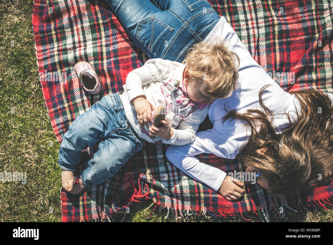 Une tendre image à partir de deux petites sœurs se reposer ensemble sur une journée ensoleillée au parc. Concept portrait de l'amitié, la fraternité et l'amour familial. Un cou Banque D'Images