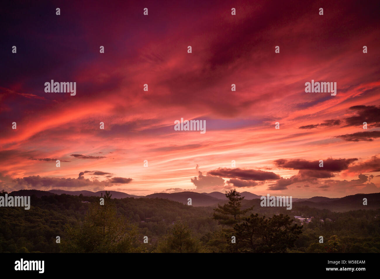 Le soleil éclaire les nuages en jaune, orange et rouge comme il se couche sur Highlands, Caroline du Nord au large de coucher de Rock. Photo © 2019 Mark Bealer Banque D'Images