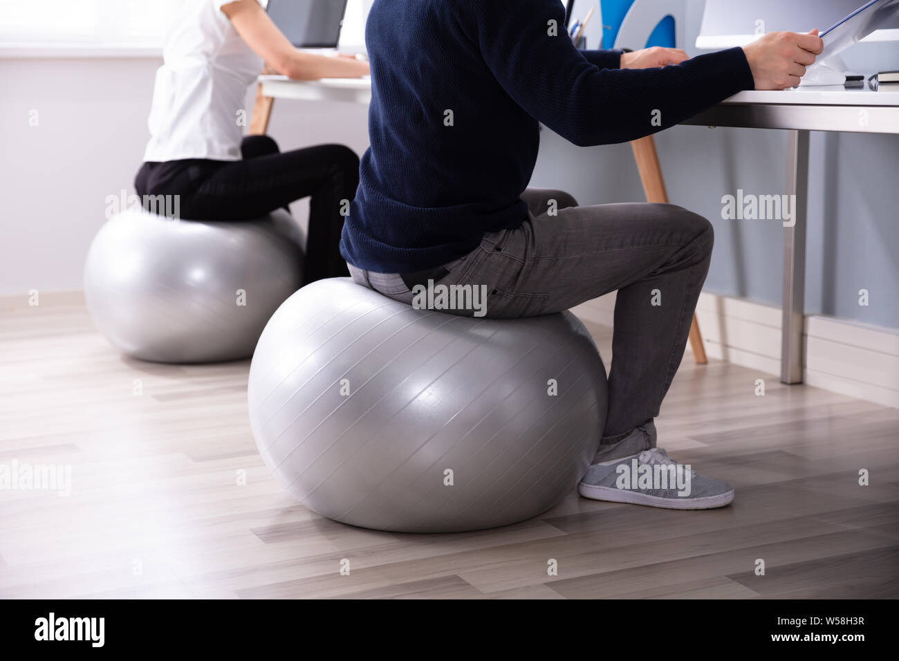 Two Businesspeople working on Computer in Office Sitting on Fitness Ball Banque D'Images