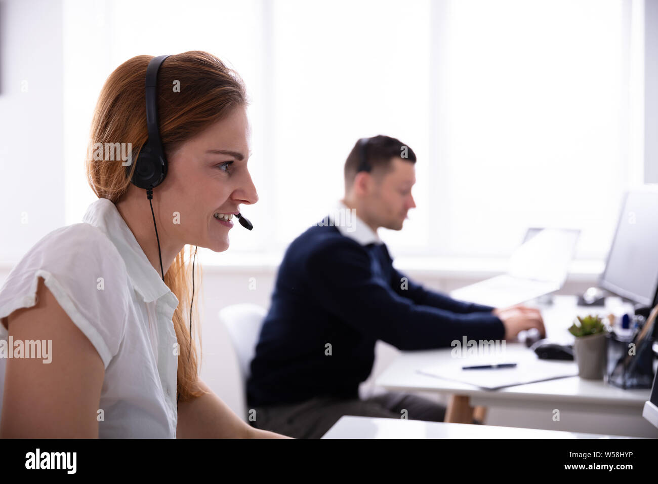Close-up of Female Telephone Operator en conversation sur des écouteurs à Office Banque D'Images