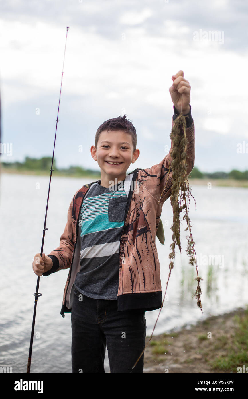 Le Tween boy holding up seaweed il surpris en action de pêche Banque D'Images