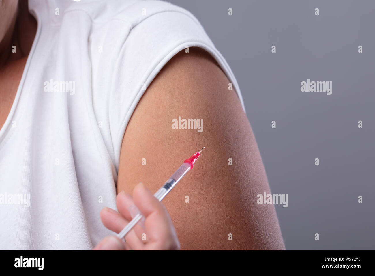 Patient Femme diabète Faire injection SERINGUE AVEC AIGUILLE sur sa main contre l'arrière-plan gris Banque D'Images