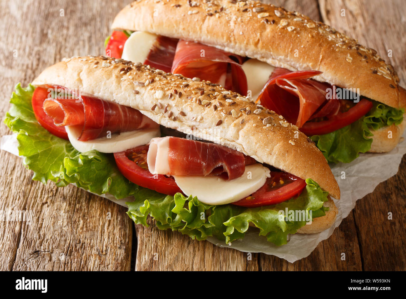 Italien copieux sandwiches avec du jambon prosciutto, fromage mozzarella, tomates et la laitue sur la table horizontale. Banque D'Images