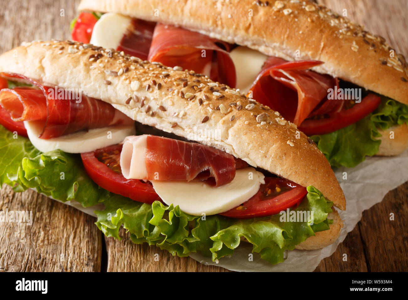 Les délicieux sandwichs avec du jambon prosciutto, mozzarella et légumes close-up sur la table horizontale. Banque D'Images