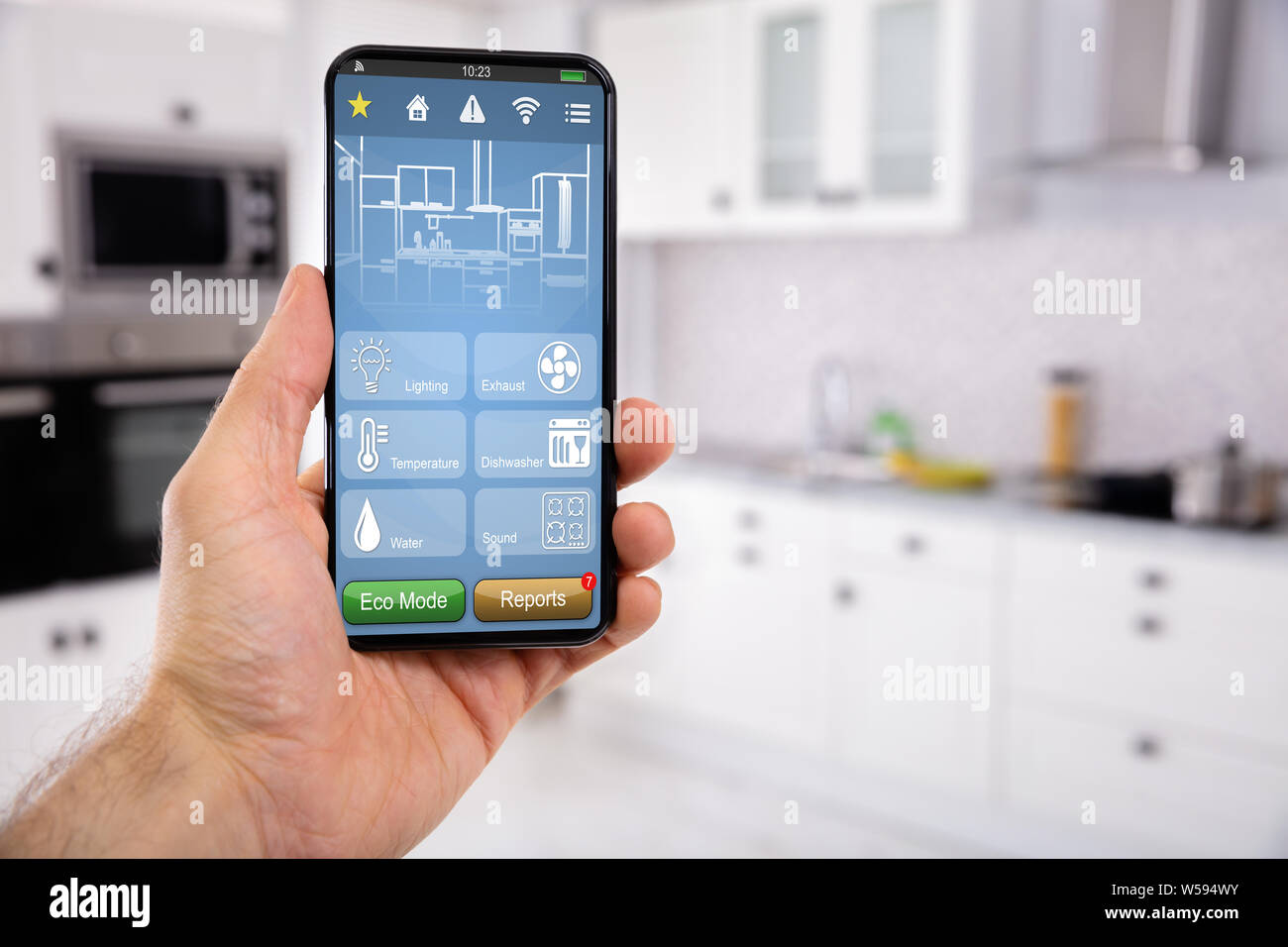 Close-up of Man's Hand Holding Mobile avec l'icône de contrôle de maison intelligente avec l'arrière-plan de cuisine Banque D'Images