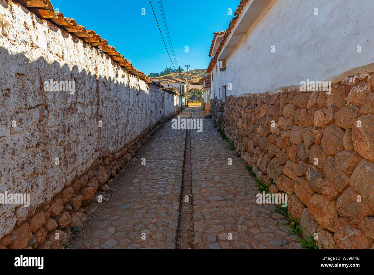 Rue de la ville de Chinchero le matin avec style inca mur architecture, pavés et de l'eau canal, Cusco, Pérou Province. Banque D'Images