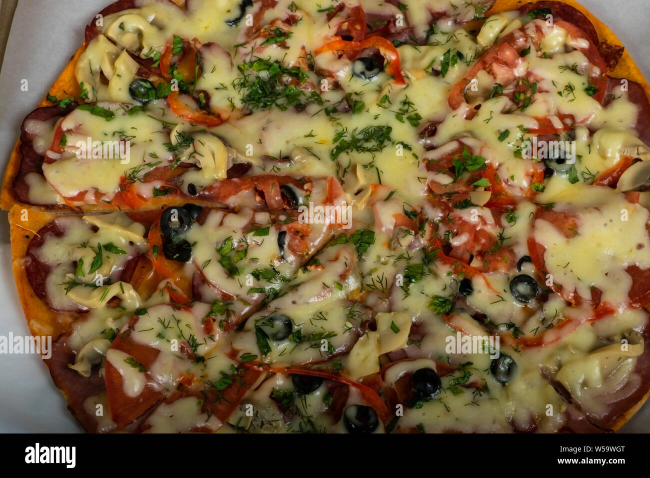 Pizza chasse avec saucisse, boeuf, tomates et olives sur la table. Banque D'Images