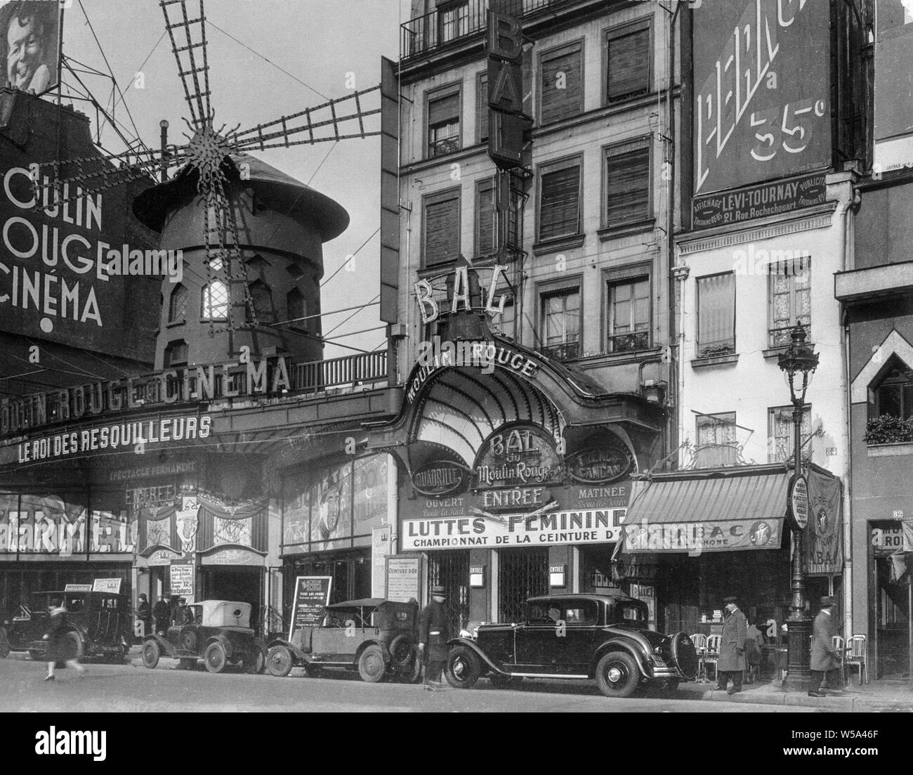 Au début du xxe siècle une photographie noir et blanc montrant le Moulin Rouge à Paris, France. Affiche également le cinéma Moulin Rouge et les voitures de l'époque. Banque D'Images