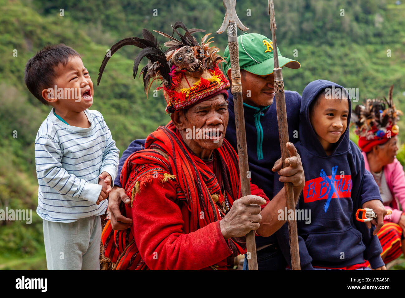 Une famille dont un enfant effrayé posent avec une tribu de Banaue, Ifugao, Luzon, Philippines Banque D'Images