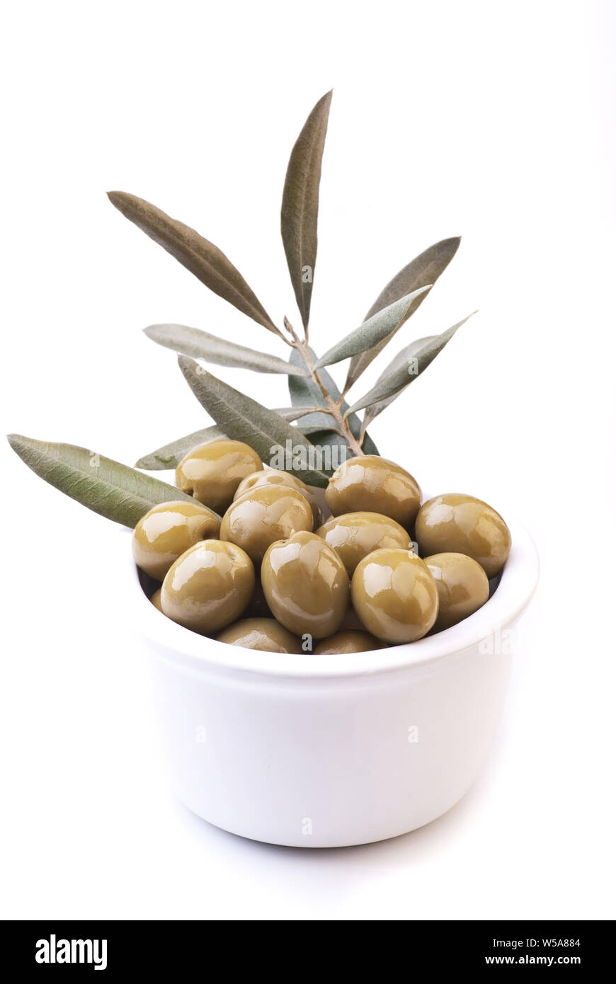Olives vertes dans le bol en céramique blanche avec rameau d'olive Banque D'Images
