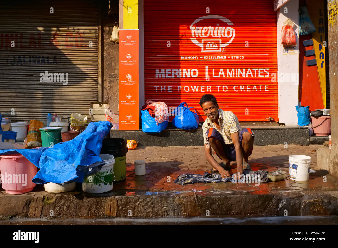 Sur un dimanche sans travail, d'un extracteur de charrettes migrants du nord de l'Inde à Mumbai, en Inde, est en train de faire sa lessive près de sa place de couchage sur le foothpath Banque D'Images