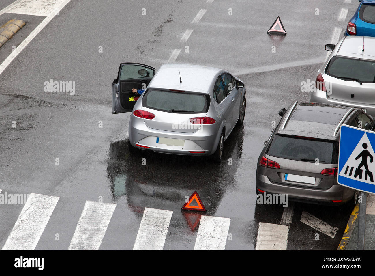 Scène d'une voiture en panne sur une route près de la rue de la ville avec un tableau de concordance et un triangle rouge pour avertir les autres usagers de la route. Jour de pluie. Copy space Banque D'Images