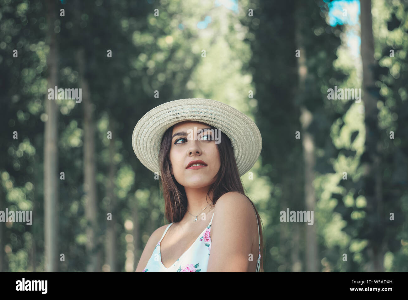 Outdoor portrait of a young attractive brunette woman wearing white sun hat Banque D'Images