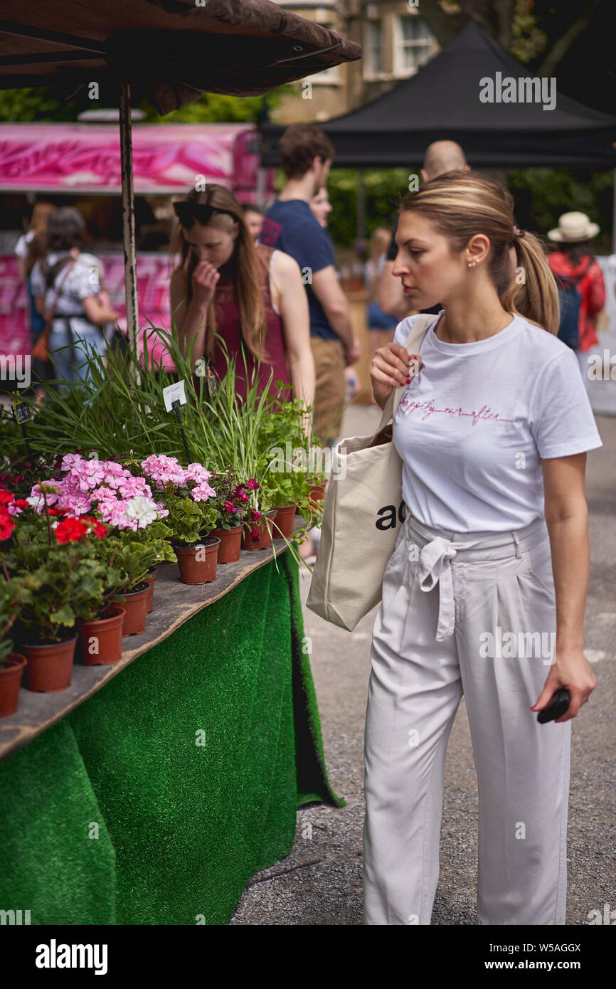 Londres, UK - juillet 2019. Les jeunes shopping pour fleurs et plantes fleuriste sur un marché de décrochage à Brockley, un marché fermier local. Banque D'Images