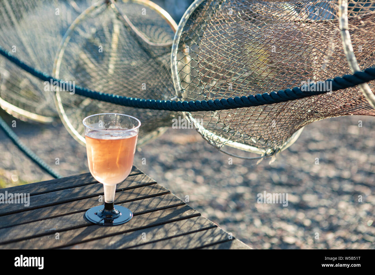 Verre de vin rose avec un filet de pêche dans l'arrière-plan Banque D'Images