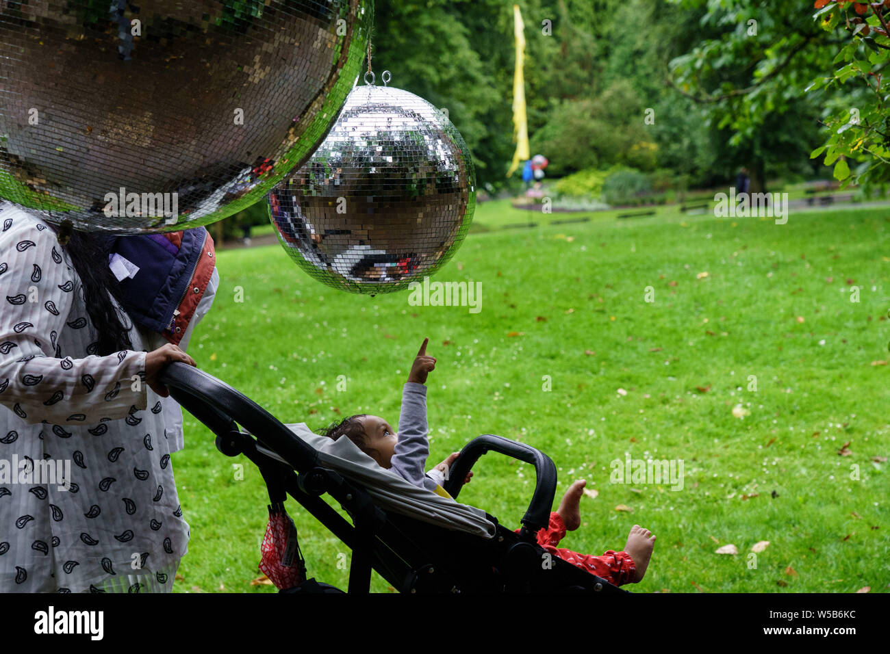 Un jeune bébé dans un Buggy pointant vers une grande boule de paillettes  suspendue au-dessus, Valley Gardens. Harrogate, Yorkshire du Nord,  Angleterre, Royaume-Uni Photo Stock - Alamy