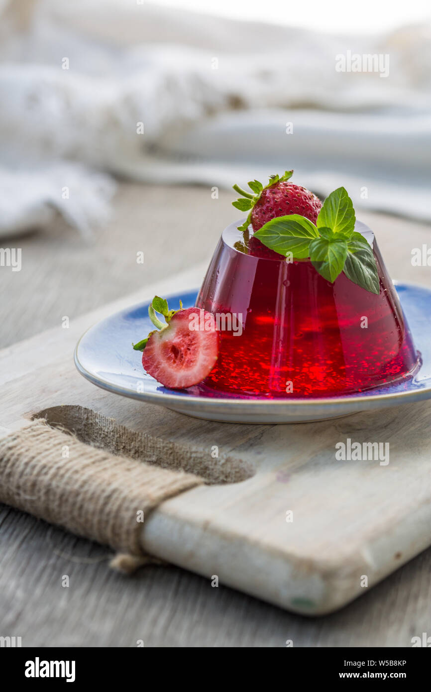 Photo de l'été Jelly dessert avec la fraise. Garni d'un brin de basilic frais sur fond clair. Banque D'Images