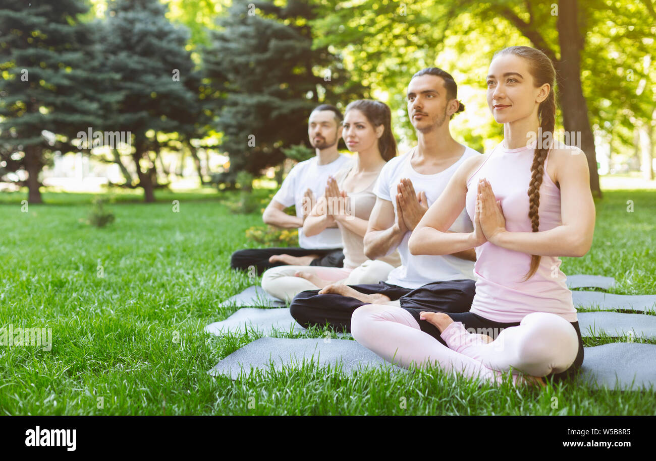 Les amis de pratiquer le yoga dans le parc faisant le geste de namaste Banque D'Images