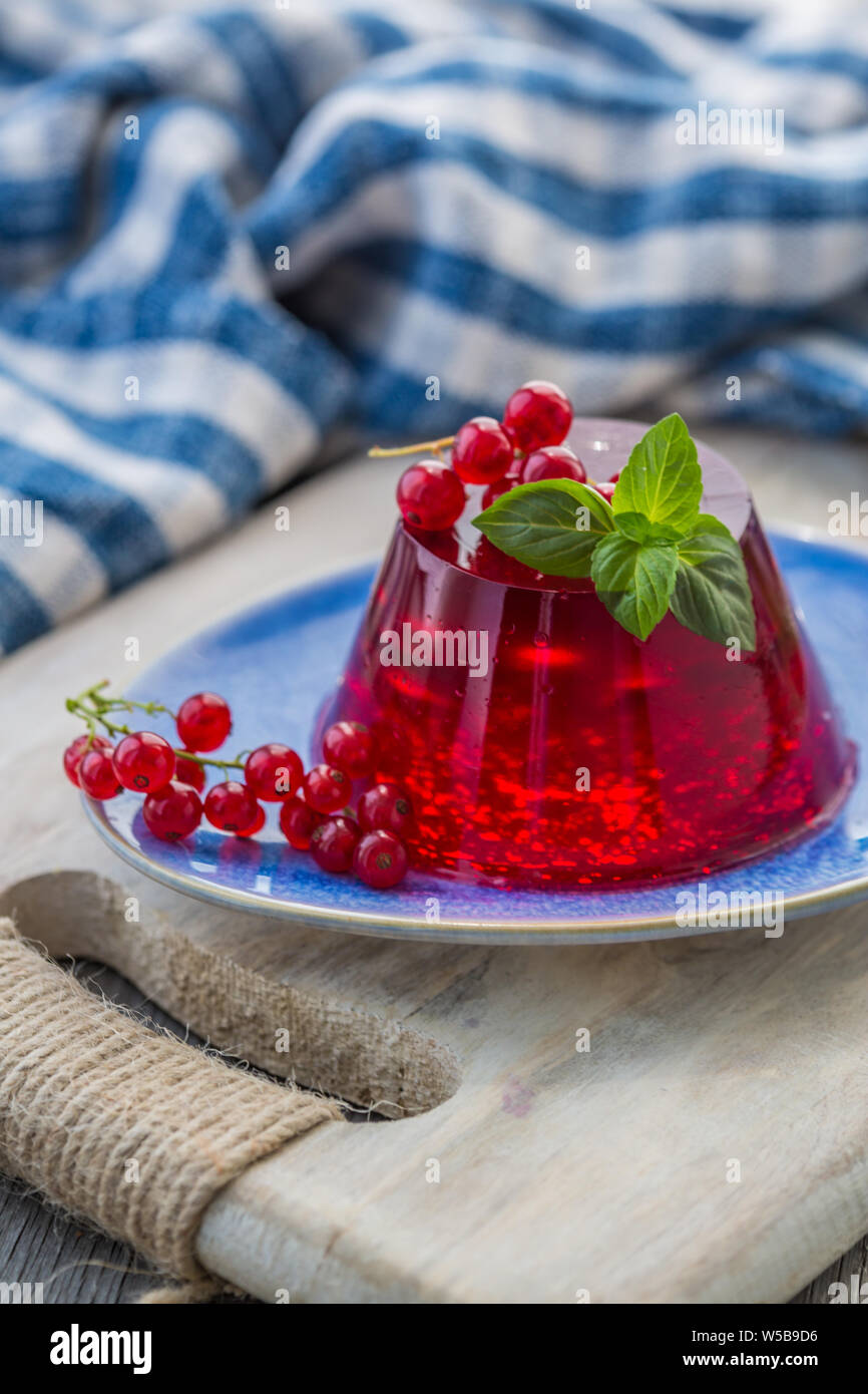 Photo d'été dessert avec de la gelée de groseille rouge. Garni d'un brin de basilic frais sur fond clair. Banque D'Images