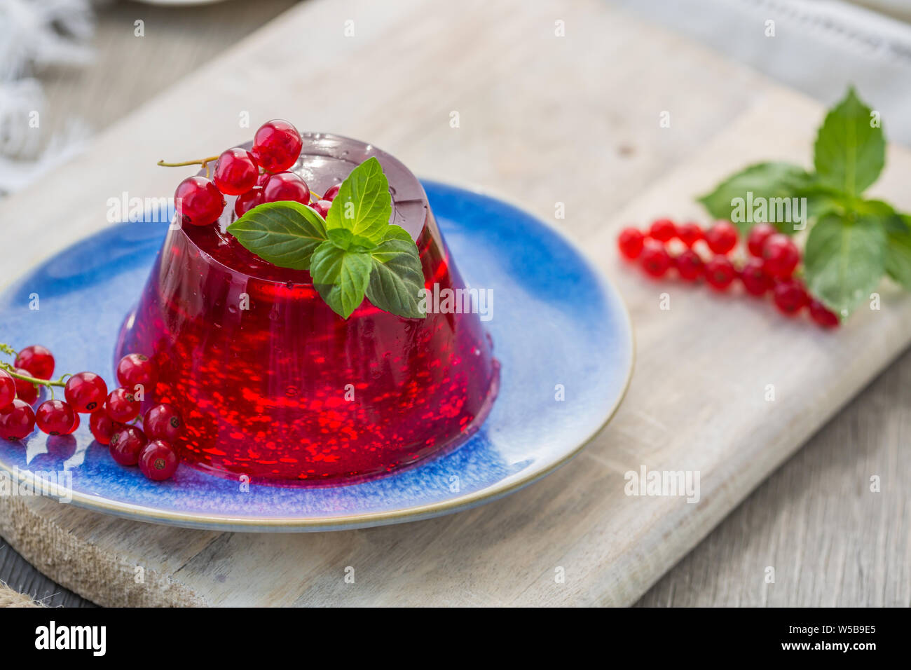 Photo d'été dessert avec de la gelée de groseille rouge. Garni d'un brin de basilic frais sur fond clair. Banque D'Images
