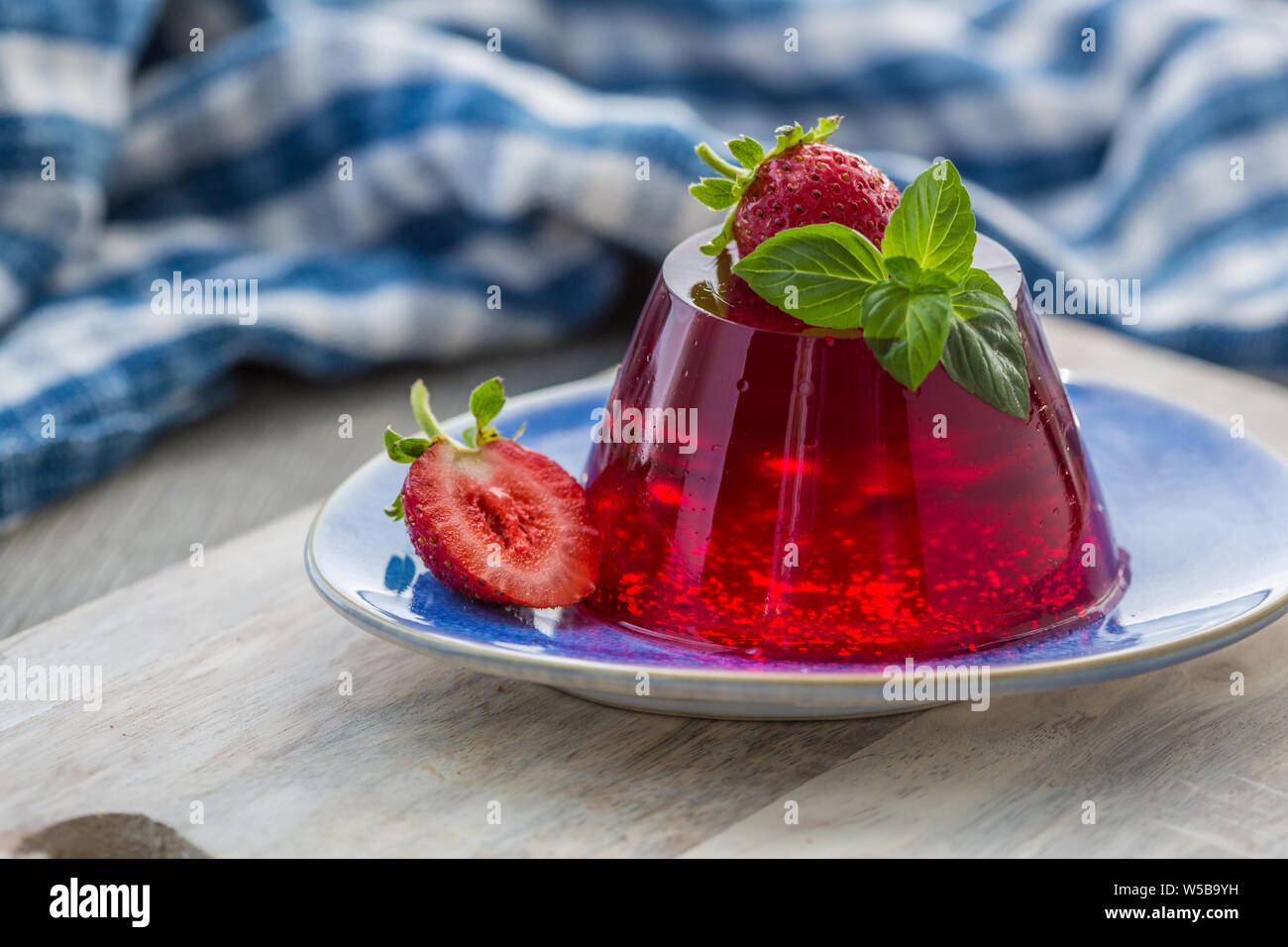 Photo de l'été Jelly dessert avec la fraise. Garni d'un brin de basilic frais sur fond clair. Banque D'Images