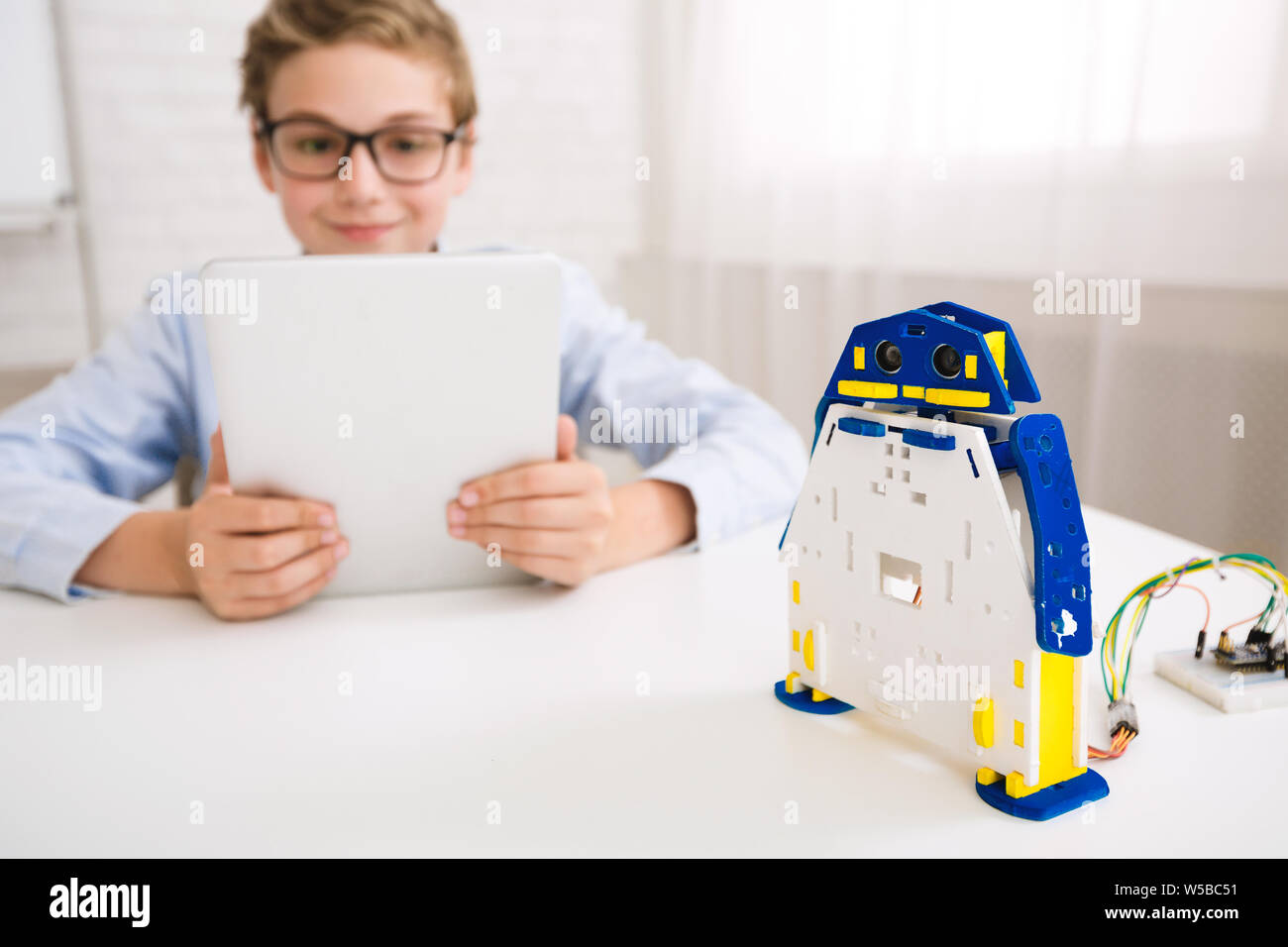 Programmation garçon robot avec tablet computer in class Banque D'Images