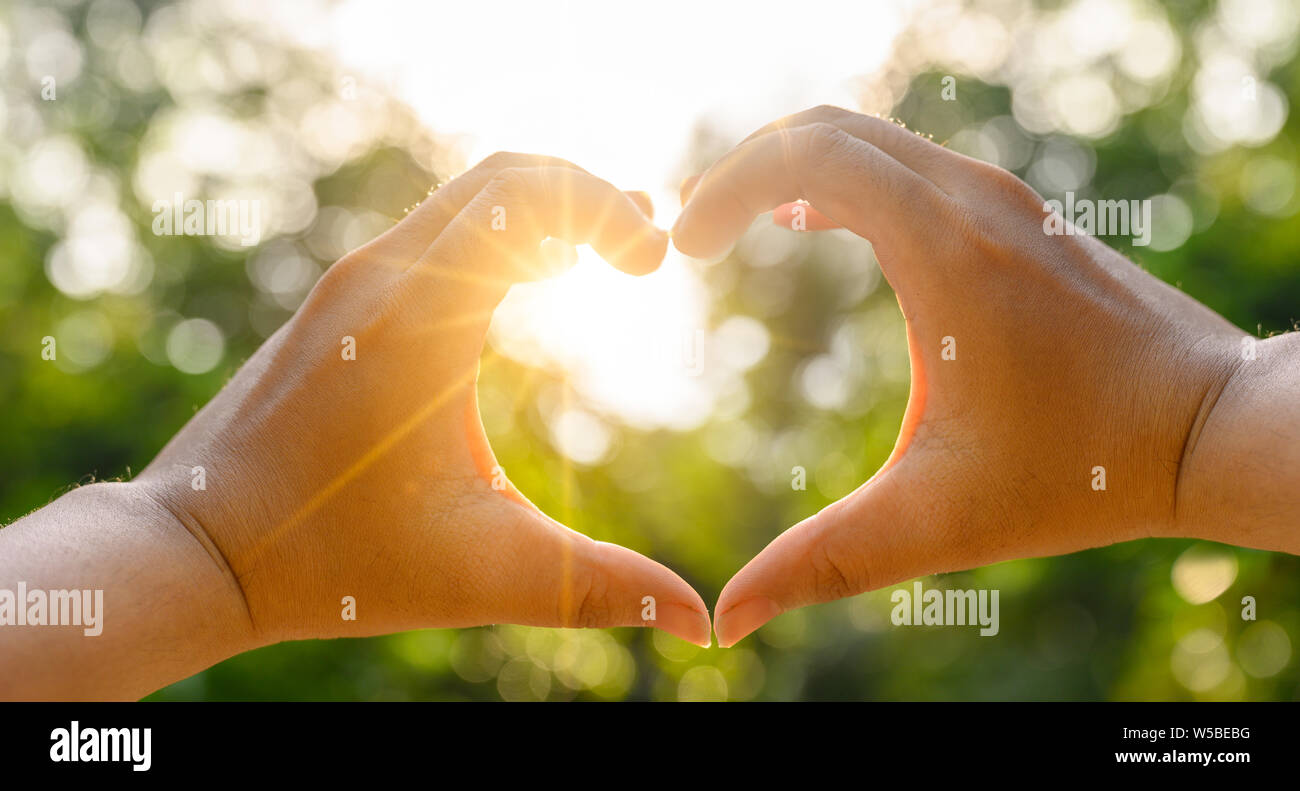 Les mains des femmes et des hommes sont la forme de coeur avec la lumière du soleil passant entre les mains Banque D'Images