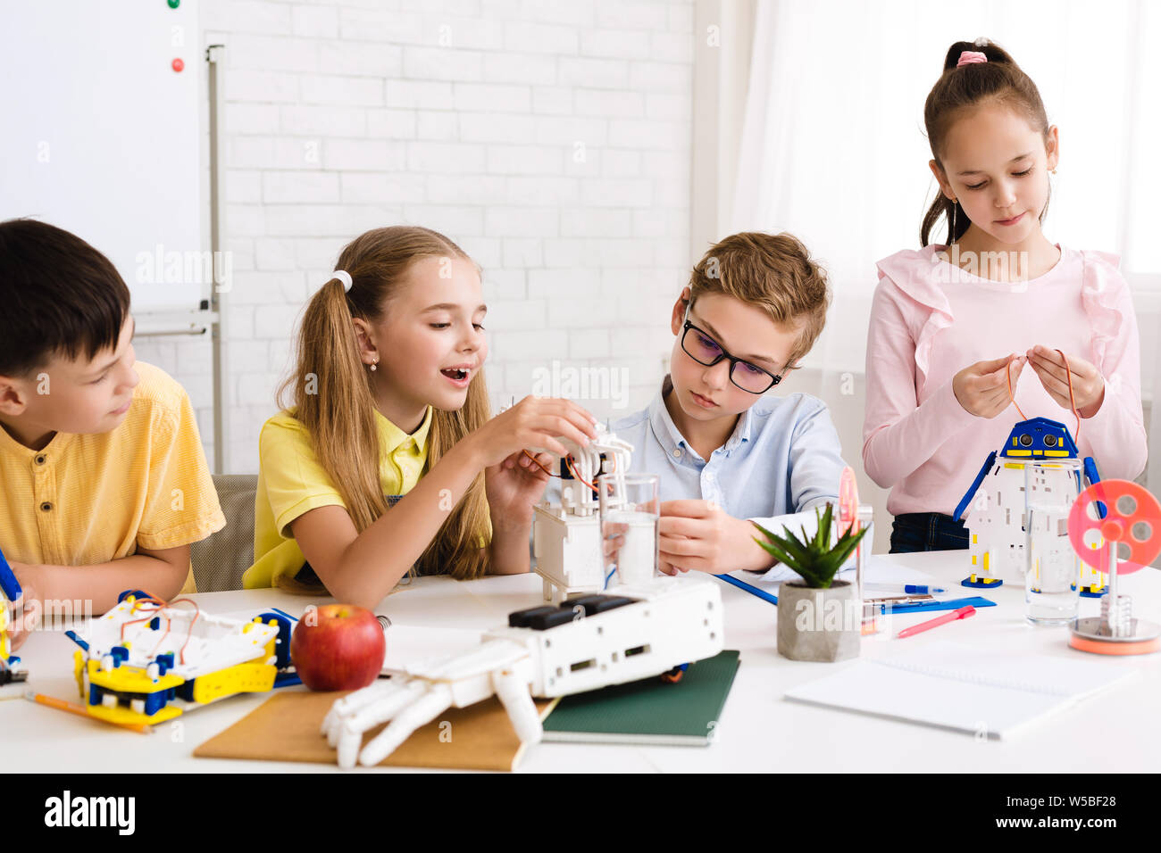 La programmation de robots enfants excités ensemble en classe de la tige Banque D'Images