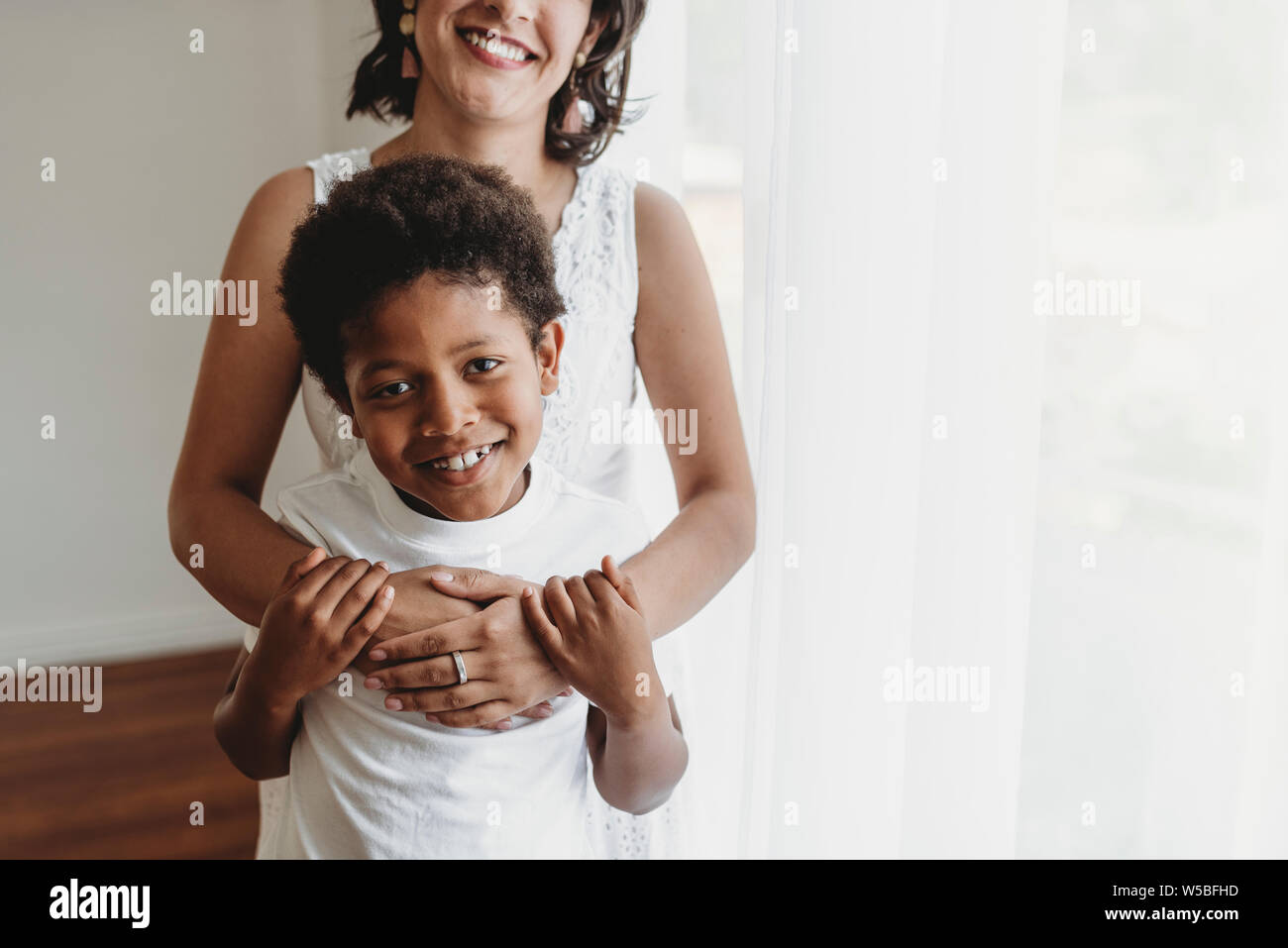 Mi-niveau view of smiling fils câlins par mère en studio Banque D'Images
