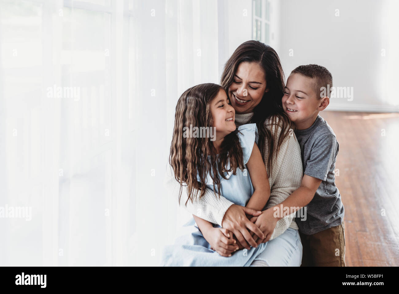 Mère, fille et fils de rire à l'autre en studio Banque D'Images