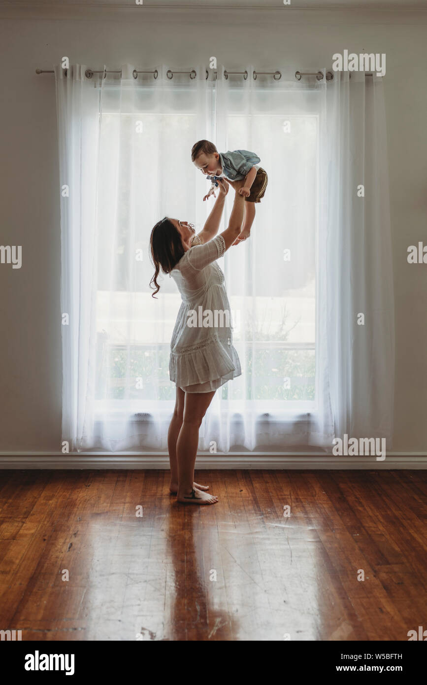 La vue de mère enceinte holding up petit garçon en studio Banque D'Images