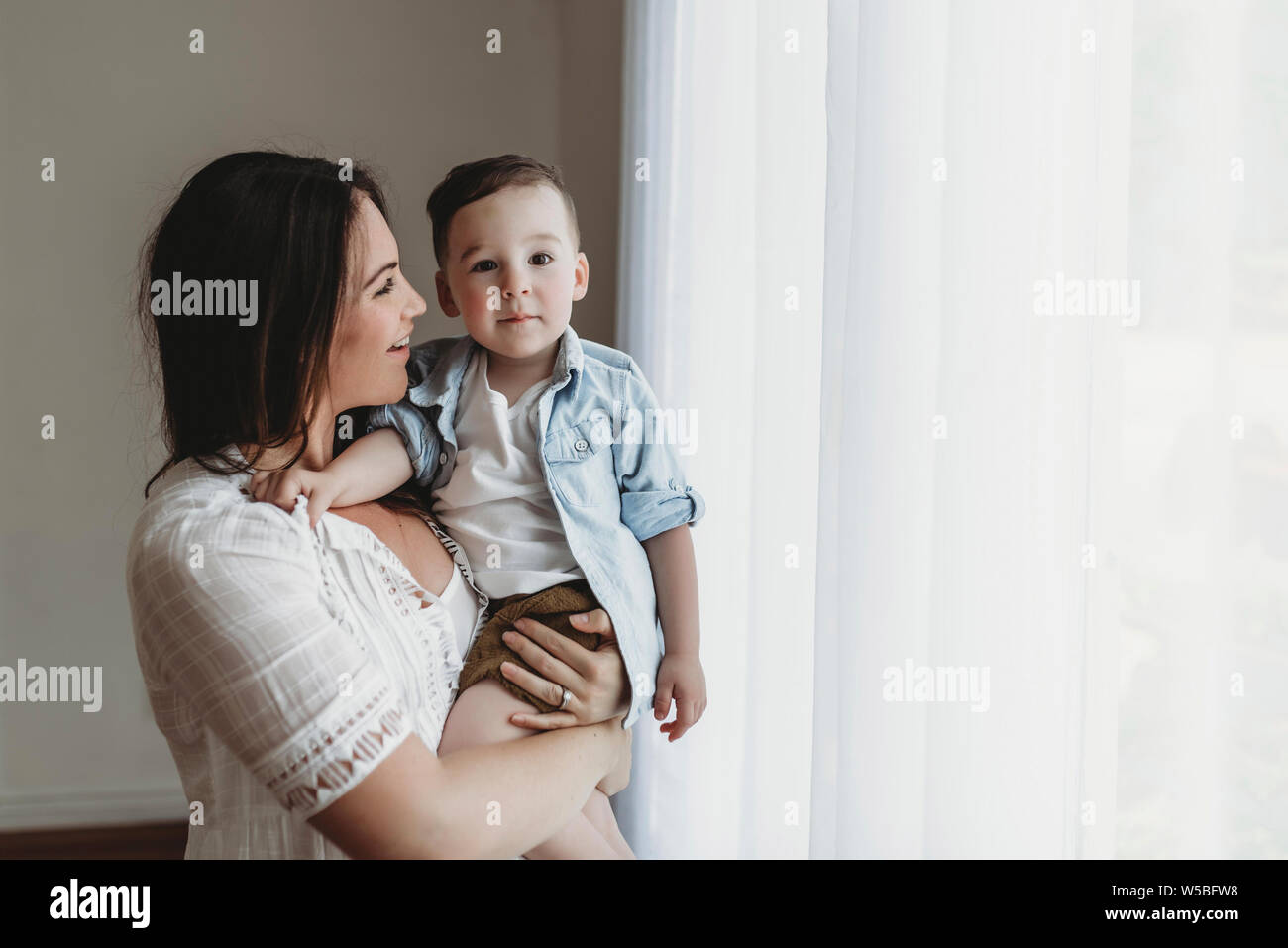 Vue de côté à la mère au petit garçon de lumière naturelle studio Banque D'Images