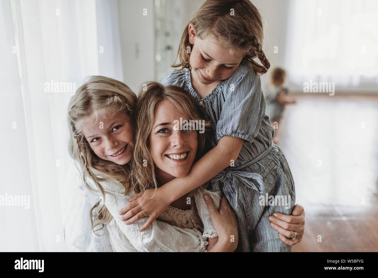 Filles embrassant smiling mother de lumière naturelle studio Banque D'Images
