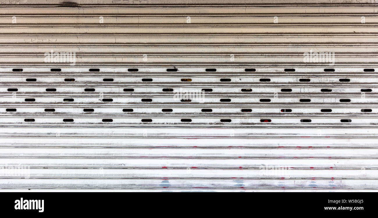 Vieux métal couleur blanc volet roulant s'est évanoui à texture de fond plein. Garage ou l'entrée du magasin vue avant Banque D'Images