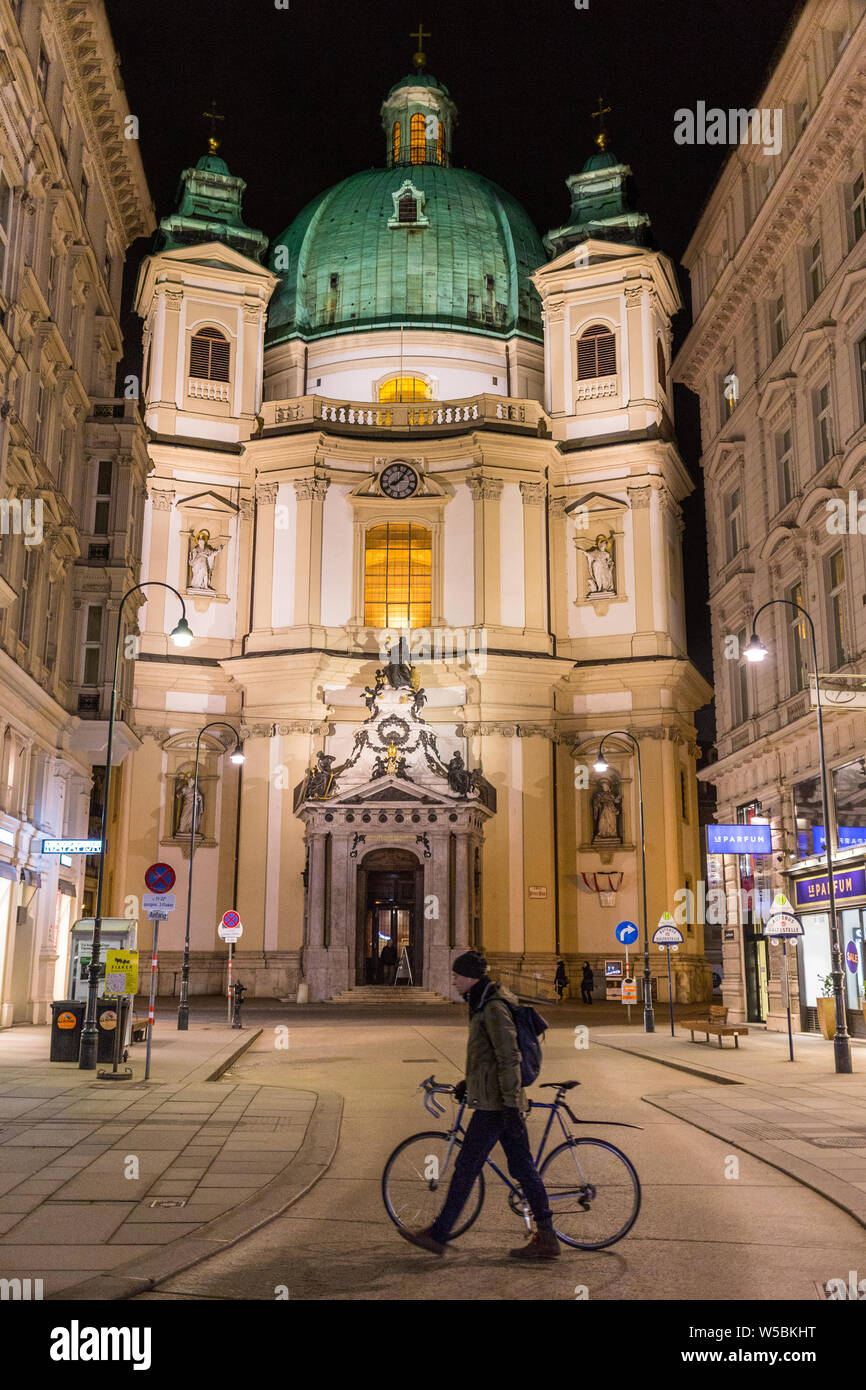 Homme avec un vélo passe devant l'église catholique Saint Pierre.Le Saint Pierre, en Peterskirche, Autrichien Baroque est un catholique romain. Banque D'Images