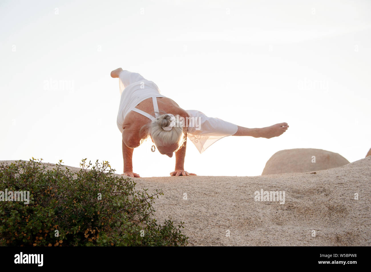 Femme Seniro dans l'équilibre du bras de yoga sur paysage de pierre. Banque D'Images