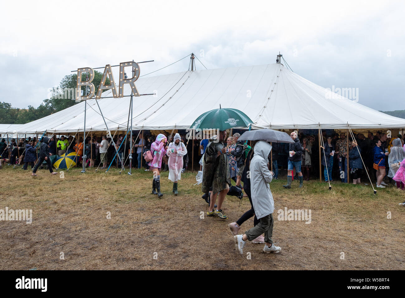 Standon, UK. Samedi 27 juillet 2019 les amateurs de festivals. s'abriter de la pluie à Standon Composant situé dans le pittoresque en raison de Standon Seigneurie © Jason Richardson / Alamy Live News Banque D'Images