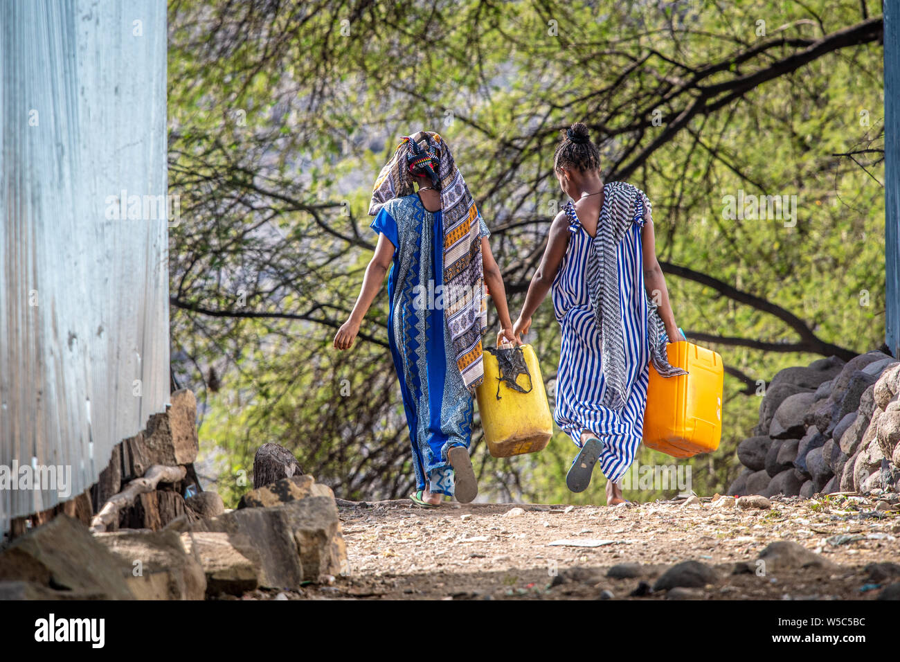 Une paire de femmes transportant des conteneurs vers le bas d'un chemin de terre, Debre Berhan, Ethiopie Banque D'Images