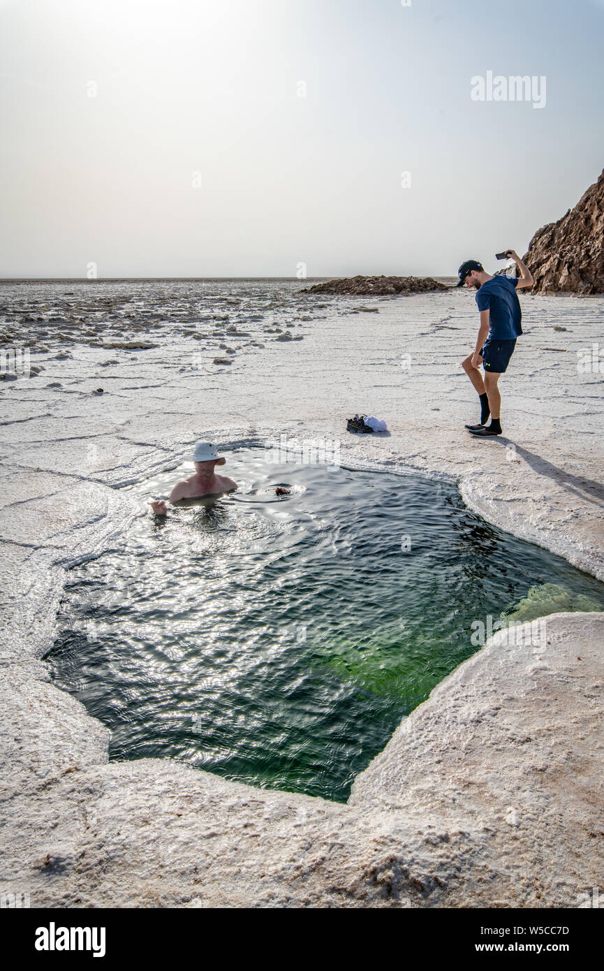 Les touristes se détendre à l'intérieur de l'eau du lac Karoum, visible à travers un trou dans le sel, dépression Danakil, l'Éthiopie. Banque D'Images