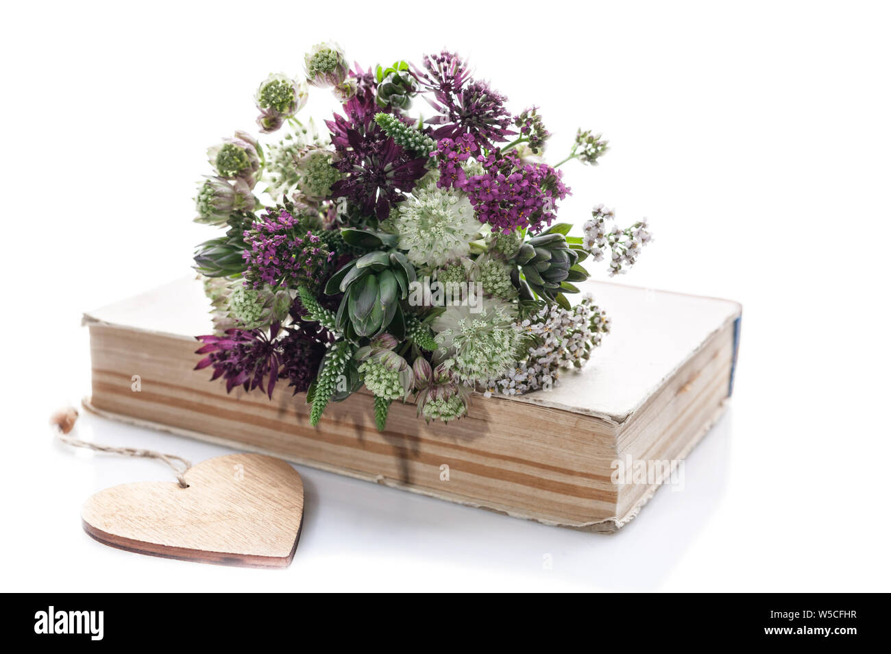 Bouquet de fleurs sauvages sur un vieux livre sur un fond blanc. Objet isolé Banque D'Images