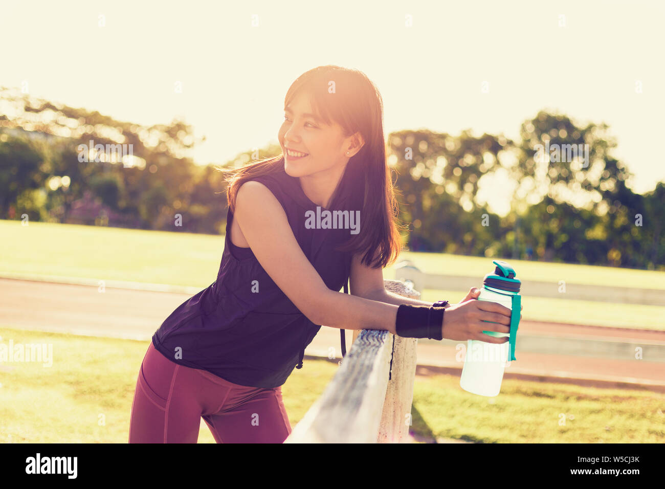 Happy Young Asian woman kissing tenant son bottole l'eau à une piscine en plein air sur le terrain un matin ensoleillé, chaud, le ton des couleurs rétro heureux Banque D'Images