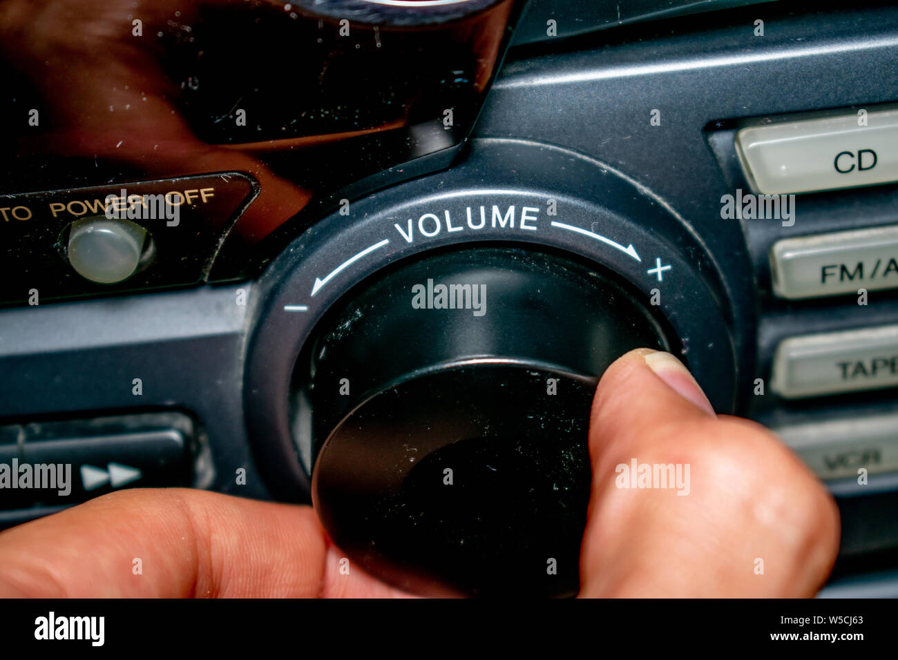 Une personne en tournant la molette du volume vers le haut ou vers le bas (l'accent est mis sur le mot 'volume' écrit sur l'appareil) Banque D'Images