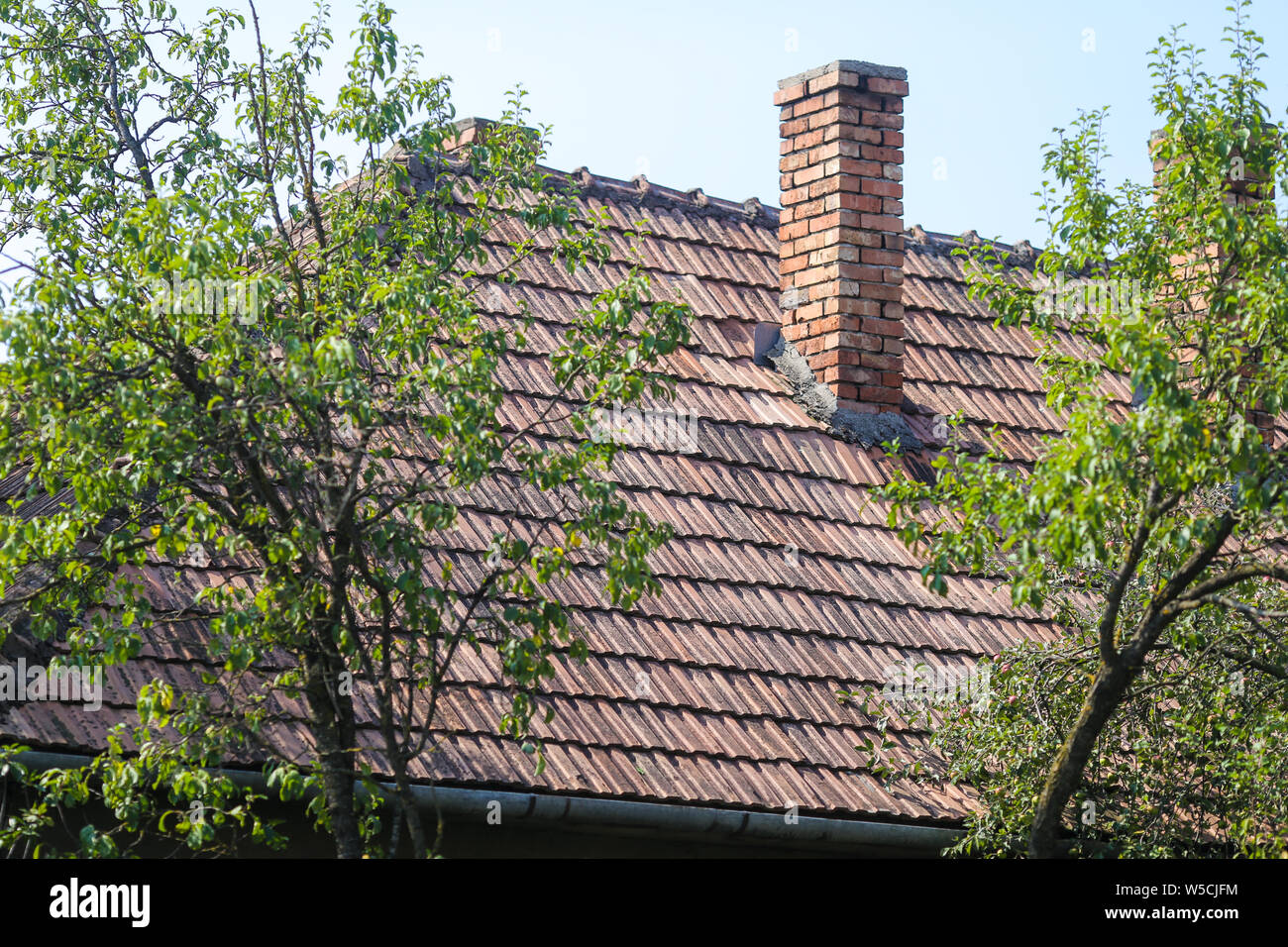 Détails avec l'ancien les tuiles et briques rouges avec la cheminée d'une maison dans un village rural en Roumanie Banque D'Images
