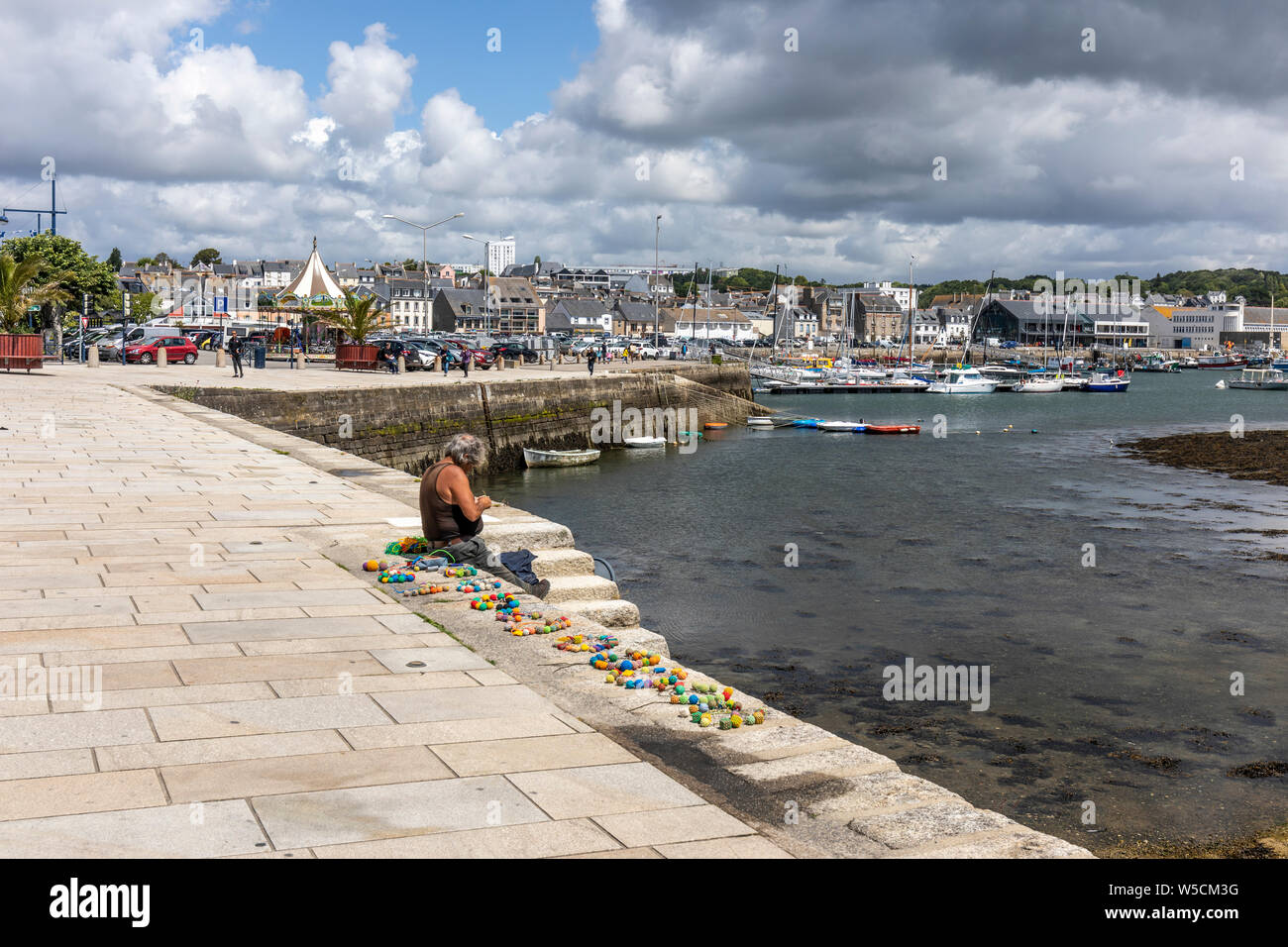 Homme assis sur le quai faire travail corde décorative de vendre à l'touristes en visite Banque D'Images