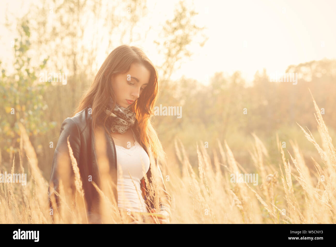 Belle jeune femme triste marche à l'herbe sèche à la bas Banque D'Images